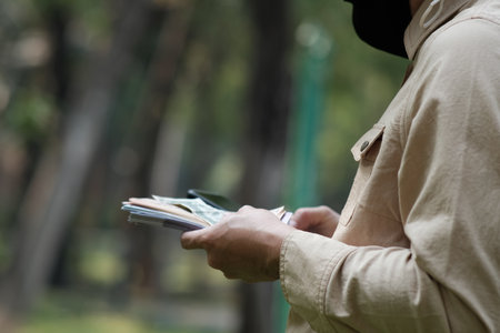 Hands holding money in garden and concept saving money, business growth strategy of money concept, advertising coins of finance and bankingの写真素材