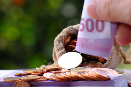 Money saving concept. Hand putting money into a piggy bank.