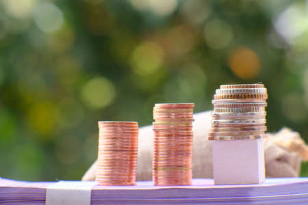 Stacks of coins on the book with green bokeh backgroundの写真素材