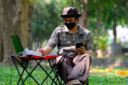 Man using smartphone in garden background and business conceptの写真素材