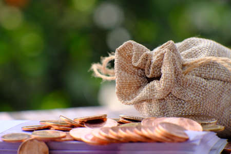Coins spilling out of a burlap bag on a green background