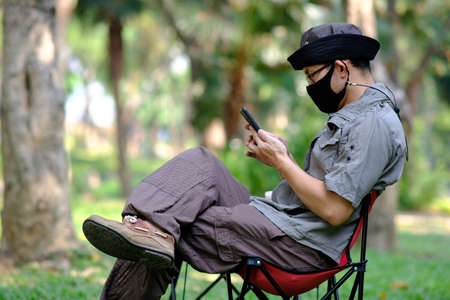 Man using smartphone in garden background and business conceptの写真素材