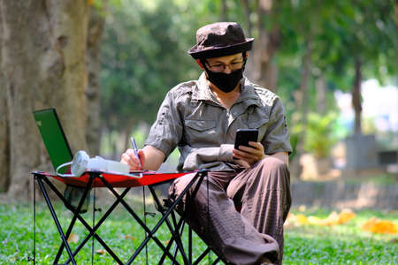 Man using smartphone in garden background and business conceptの写真素材