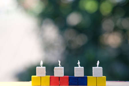 Miniature people standing on wooden block with blurred background. Business and teamwork concept.の写真素材