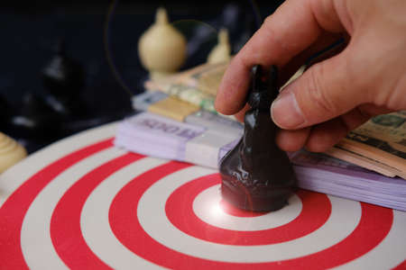 Businessman putting money into a dartboard. Business concept. Close up.の写真素材