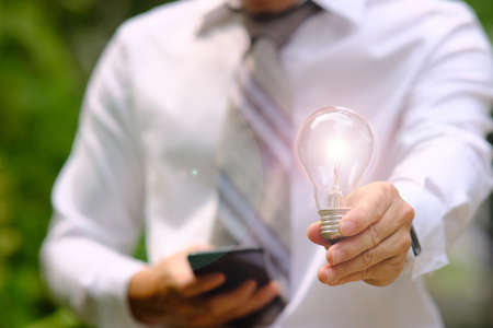 Hand holding energy saving light bulb and business growth concept,Creative new ideaの写真素材