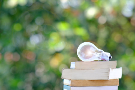energy saving light bulb and book on tableの写真素材