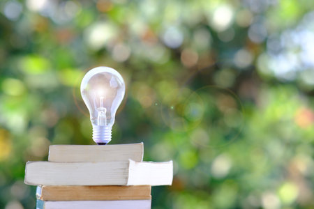 energy saving light bulb and book on tableの写真素材