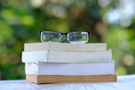 Books on a wooden table and Education learning concept with open book or textbook in library, stack piles of book on tableの写真素材