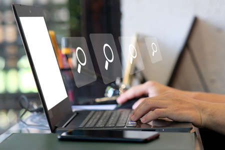 Search engine optimization (SEO) concept. Businessman using laptop computer with magnifying glass icon.の写真素材