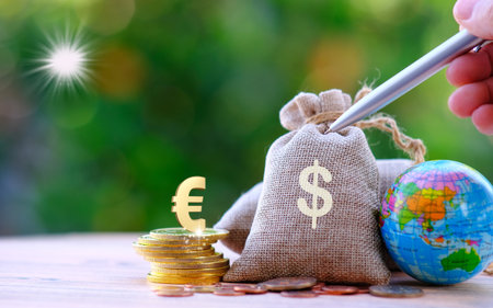 Money bag with coins and globe on wooden table with green background.の写真素材