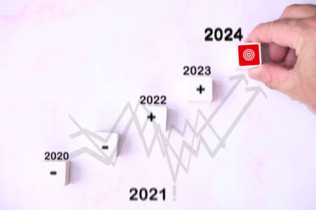 Business and finance concept. On a pink background, a man's hand holds a red dart with the inscription 2021.の写真素材