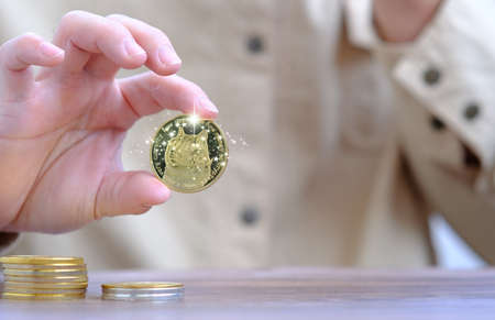 Gold coin on the table. Businessman holding a gold coin in his hand.の写真素材