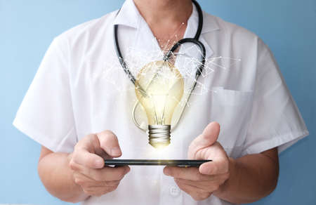 doctor holding a tablet computer with light bulb on blue background, Idea concept