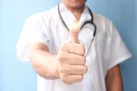 Doctor with stethoscope showing thumbs up on blue background, closeupの写真素材