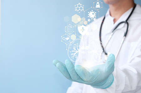 Medicine and health care concept. Doctor hand with stethoscope holding medical icons on blue...