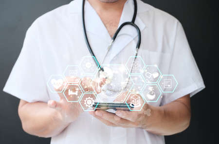 Medical doctor working with smart phone and stethoscope in modern hospital with virtual icon diagram