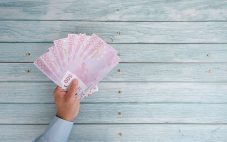 Hand holding banknotes on a blue wooden background