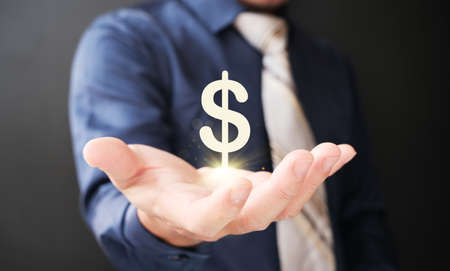 Businessman holding dollar sign in his hand on dark background, closeup