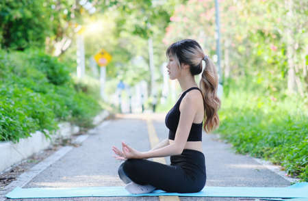 Beautiful young asian woman practicing yoga and meditation in the park.の写真素材