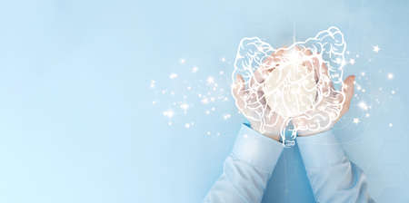 Close up of human hands holding brain on light blue background with copy space