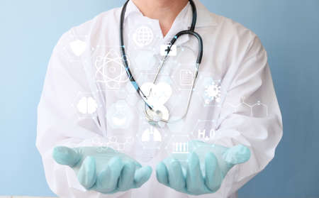 Doctor holding virtual screen with medical icons on blue background, closeupの写真素材