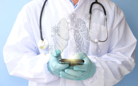 Doctor with stethoscope and mobile phone on light blue background, closeupの写真素材