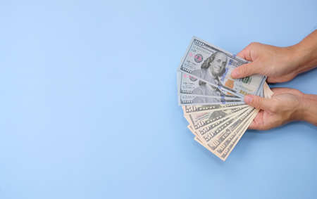 Hands counting money on light blue background, closeup. Space for textの写真素材