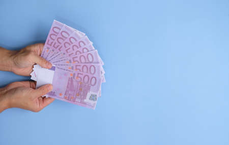 Woman holding money on light blue background, top view. Space for textの写真素材