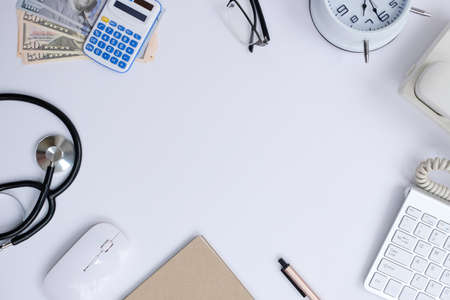 Top view of doctor workspace with stethoscope, calculator, computer keyboard, notepad and money on white background.の写真素材