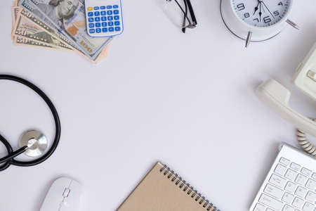 Top view of doctor workspace with stethoscope, calculator, computer keyboard and money on white background.の写真素材