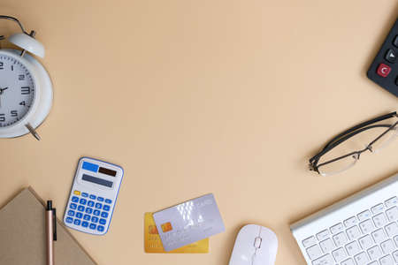 Flat lay of workspace with laptop, credit card, calculator and eyeglasses on beige background.の写真素材