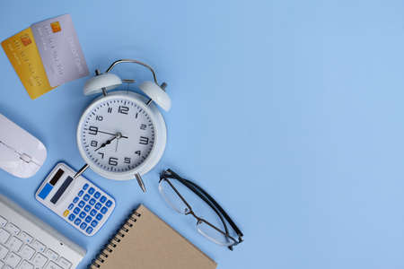 Flat lay composition with alarm clock, calculator and stationery on light blue background. Space for textの写真素材