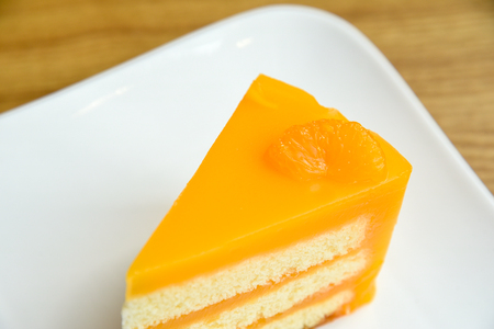 Orange cake in a white plate on wooden background ,  fruit cakeの写真素材