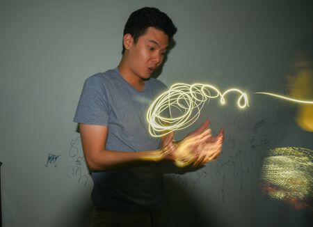 Asian man light painting curves in the dark,  light painting .