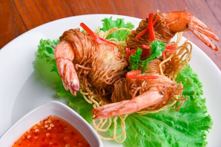Goong Sarong  noodles Wrapped Shrimp With Crispy Noodle Serve, vegetable and sauce in white plate  on wood table , Thai foodの写真素材
