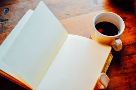Top view Hot coffee with milk and open notebook  in white cup on the table in the morningの写真素材