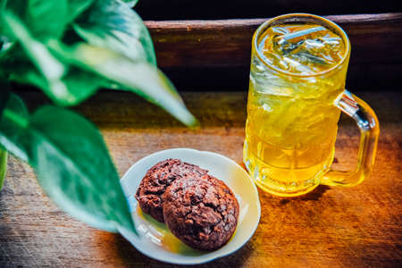 Chinese Chrysanthemum Tea in tall glass and  Brownie cookies on wood table, health herbal tea.の写真素材