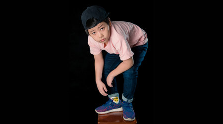 Cute little boy dressed in a pink shirt standing with  in a studio. Isolated on dark  background.Close up portraitの写真素材