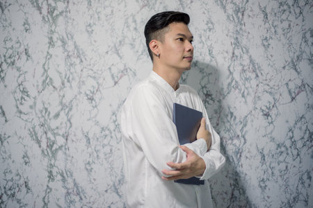 Handsome young smiling is holding a notebook and smiling at officeの写真素材