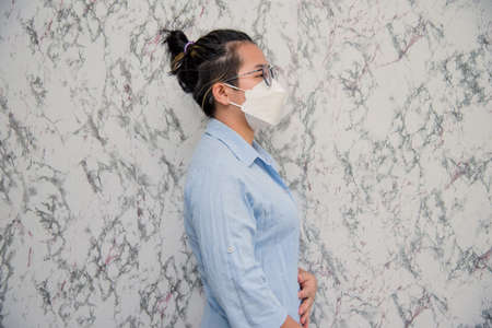 Woman puts on a face mask standing with crossed arms protecting from virus during quarantine isolated on White background,pandemic and social distancing conceptの写真素材