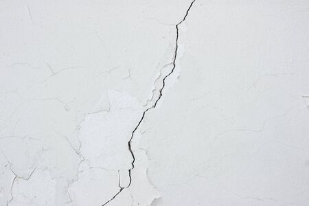 Crack on a white wall with outdated plaster.