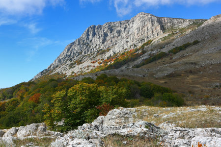 Picturesque mountain rocky peak and surrounding mountain landscape on a sunny autumn day. The peak 'Eklizi-Burun' is one of the highest peaks of the Crimean mountains.の写真素材