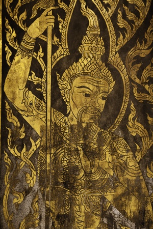 In this picture the wooden door is painted in gold color to shows the high spirit angels in the Thai beliefs. The angels are always at the doors of Ubosot buidlings to protect and salute Lord Buddha.のeditorial素材