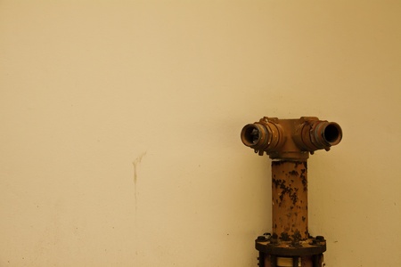 The old red water hose is among the yellowish plain wall.の写真素材