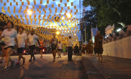BANGKOK - NOVEMBER 17 : The marathon runners are on their way to the goal while the Buddhism monks are also on their way to the temples in 17 November 2013 at banglumphoo Bangkok Thailand. These marathon runners are with Standard Charter Bangkok Marathon のeditorial素材