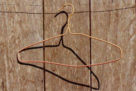 A coat hanger hang on the wire with Thai style house wich wall made from wood.の写真素材