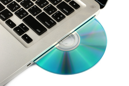 DVD, CD disk in the drive of a laptop white background, close-up, isolatedの写真素材