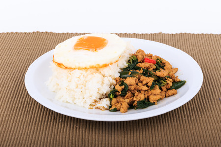 Rice topped with stir-fried chicken, basil and fried egg, fried stir basil with minced chicken on white background Isolated Backgroundの写真素材