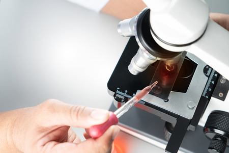 Young Asian student boy and white microscope in science laboratory with red liquid and dropper for...
